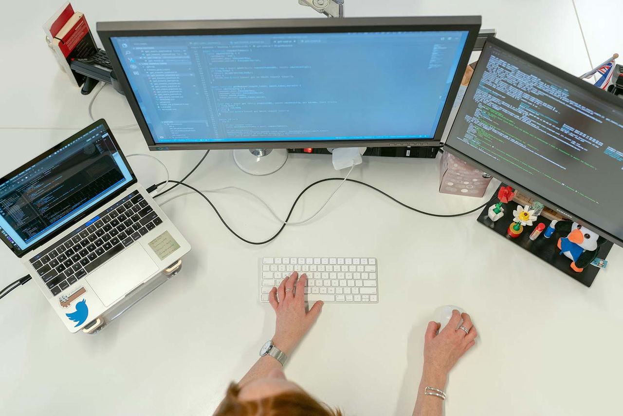 Zwei Mitarbeiter, die mit einer Formmaschine mit überlagerten Grafiken aus der cloudbasierten Infrastrukturanalyse von Minitab arbeiten.