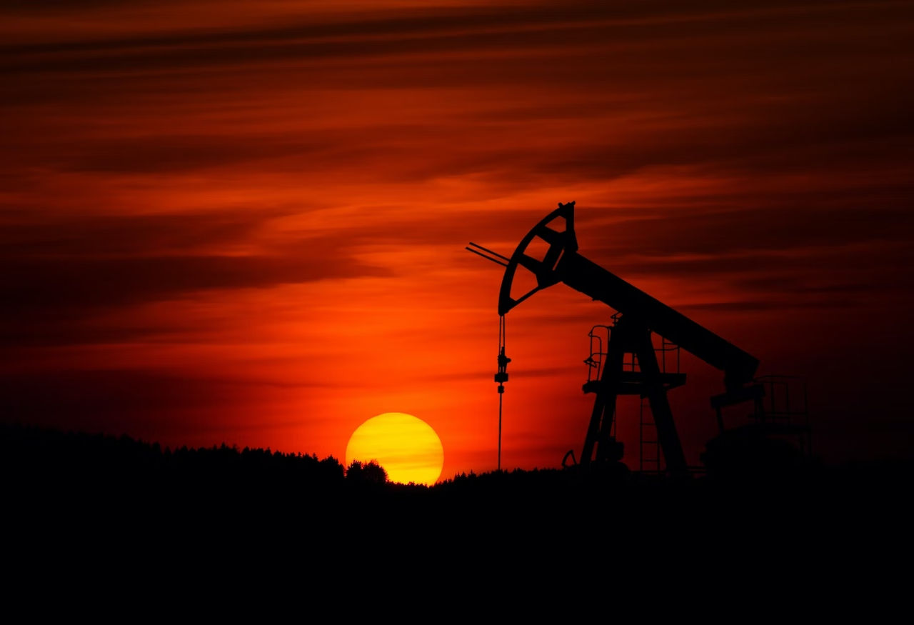 Un pozo petrolero con un atardecer de fondo